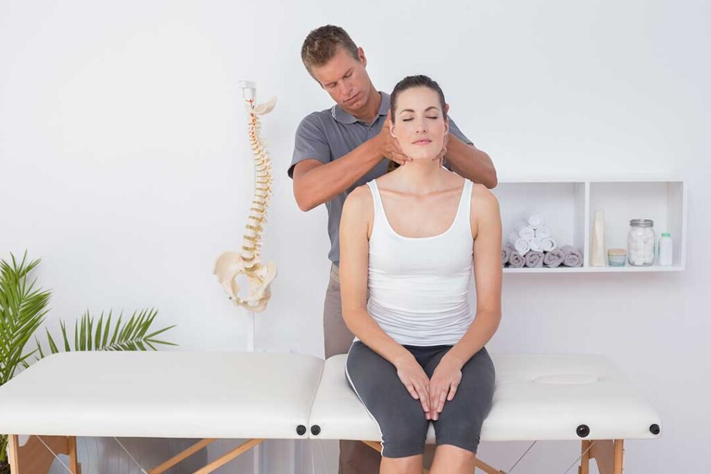 A chiropractor performing a gentle spinal adjustment on an adult seated in a calm clinical setting.