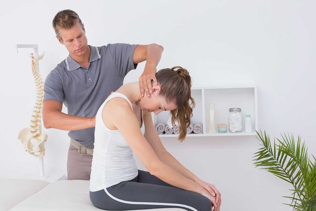 Person applying a wrapped cold pack to the lower back while resting at home