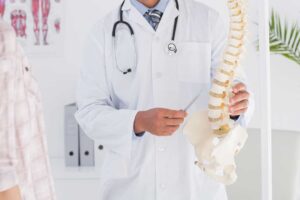 A practitioner gently adjusting a patient’s spine next to a therapist massaging a person’s neck and shoulders.